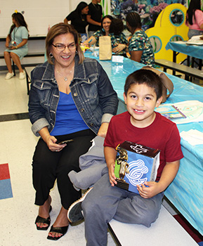adult and student raffle winner smiling while holding prize